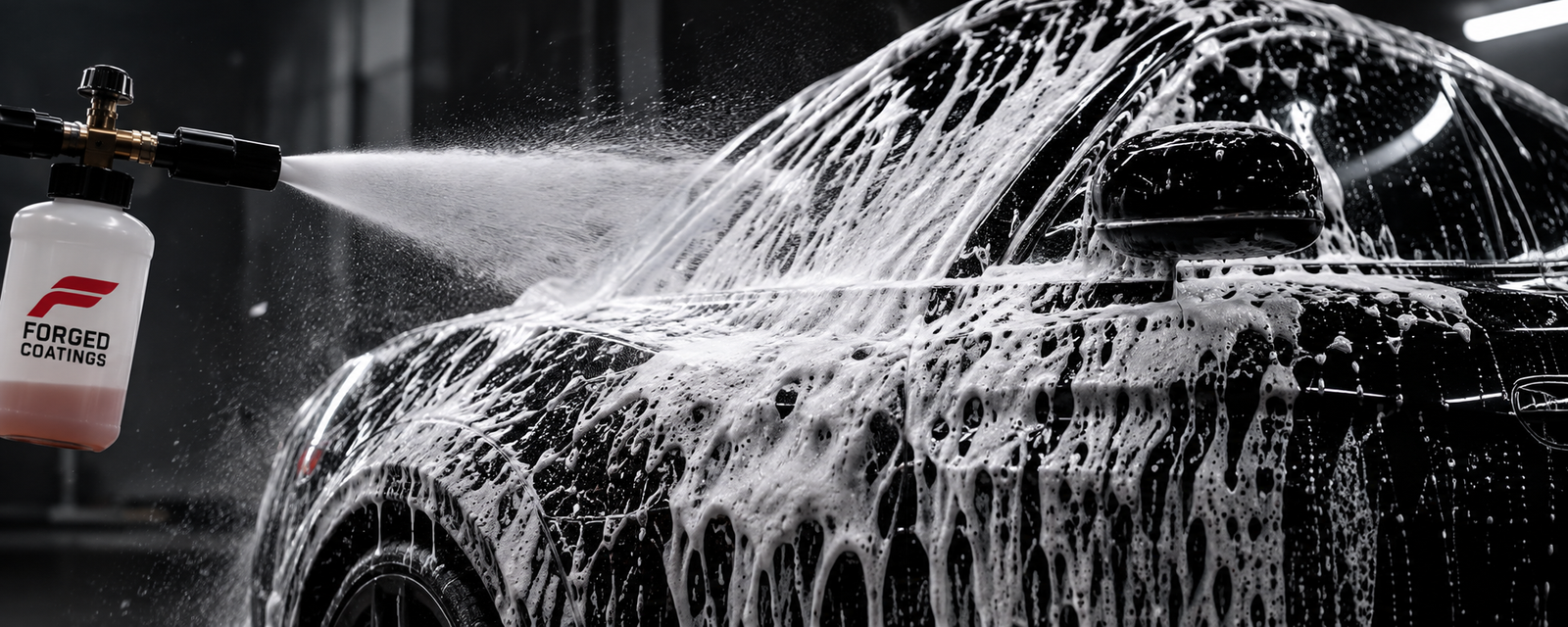 Foam cannon applying thick foam to a black vehicle